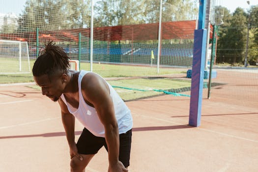 Tired athlete resting after exercise on a sunny outdoor sports field.